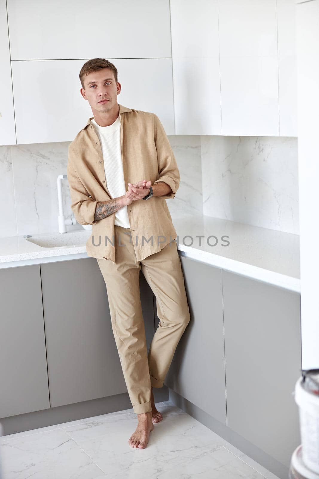 Happy handsome man is standing on minimalistic kitchen and smiling