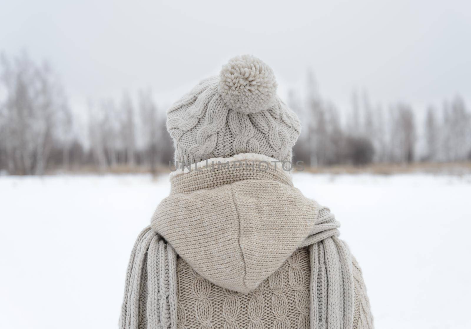 Lonely woman stands back in a field in winter