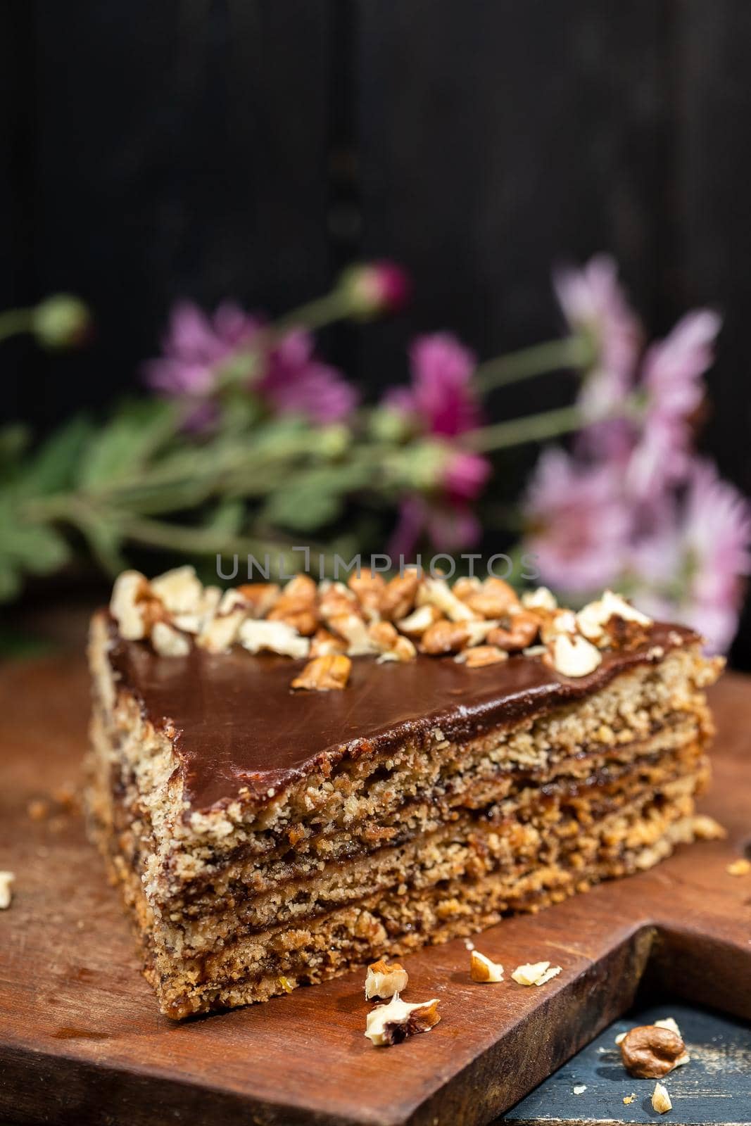 Piece of cake with walnuts on a dark wood background