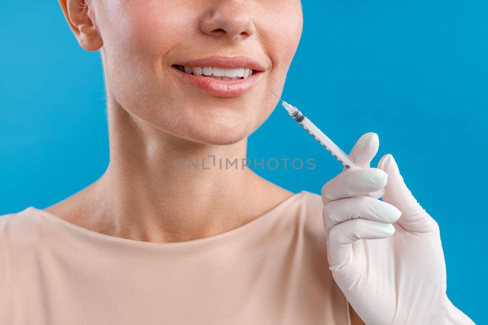 Close up shot of smiling woman receiving botox injection in lips from beautician. Beauty concept