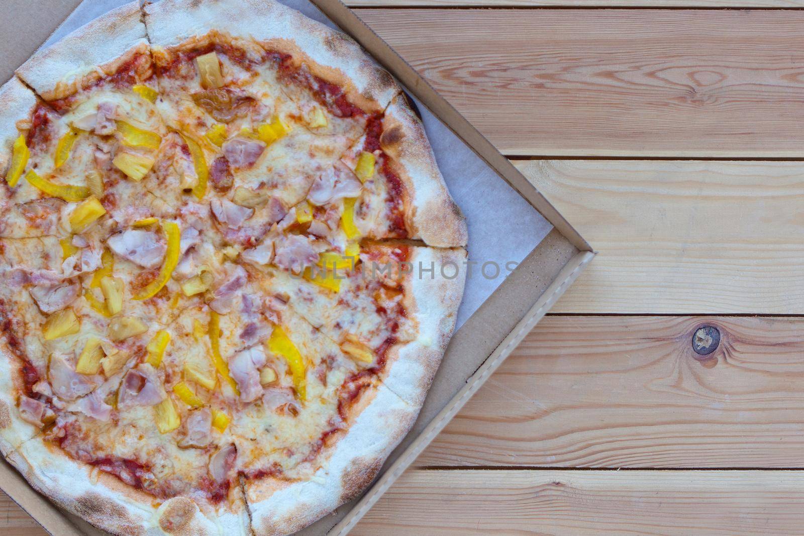 Italian Pizza in a cardboard box on wooden background. Space for text. View from above. Pizza delivery. Pizza menu.Pizza Tonda Romana