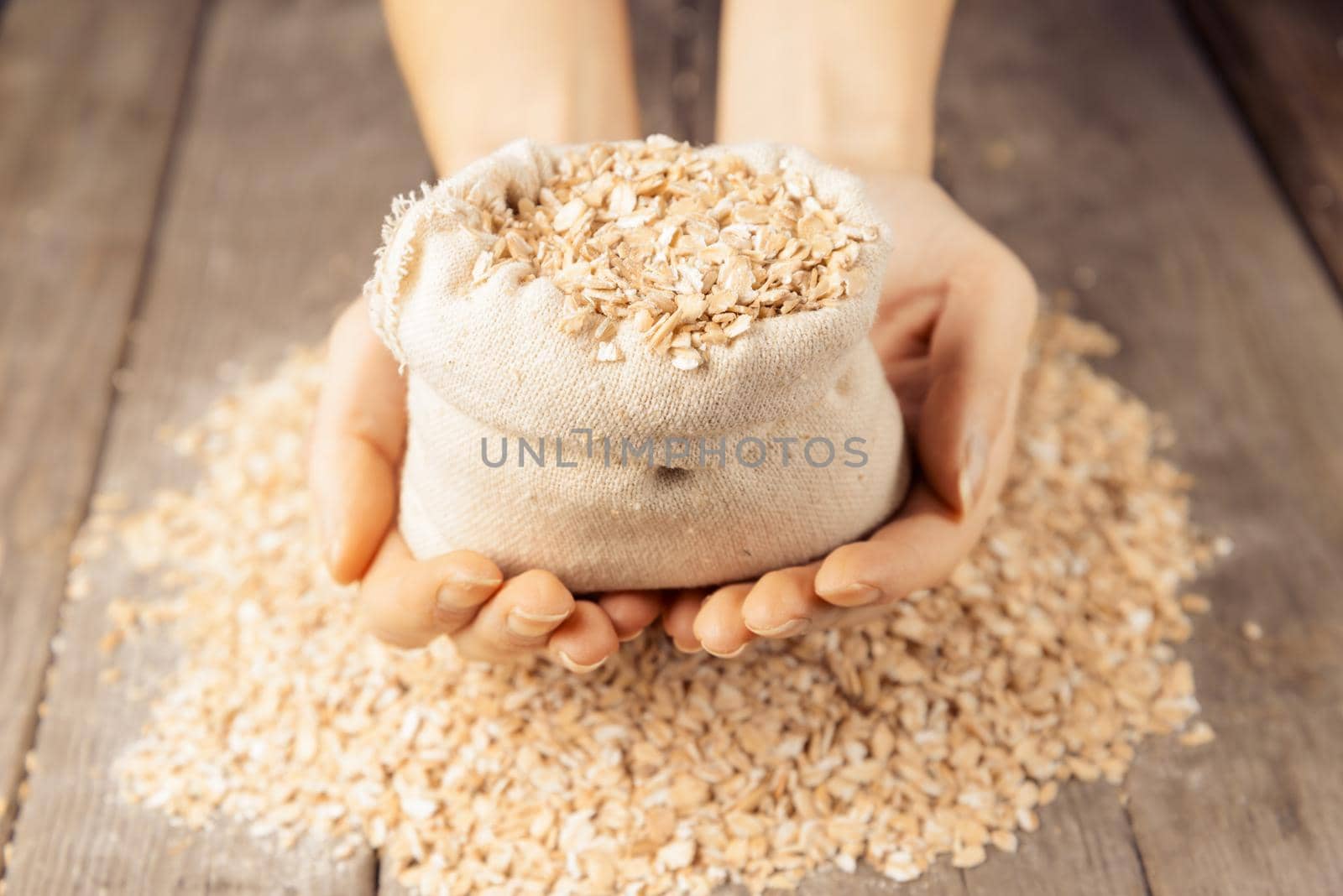 Oat flakes in a bag in the hands on a wooden background