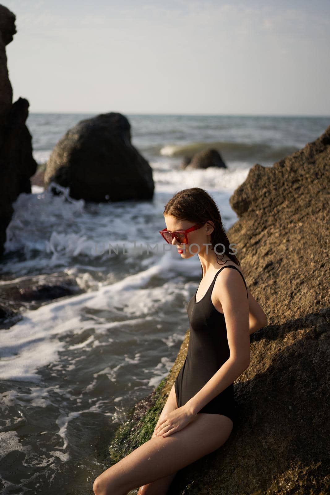 woman in swimsuit sunglasses ocean rocks posing by Vichizh