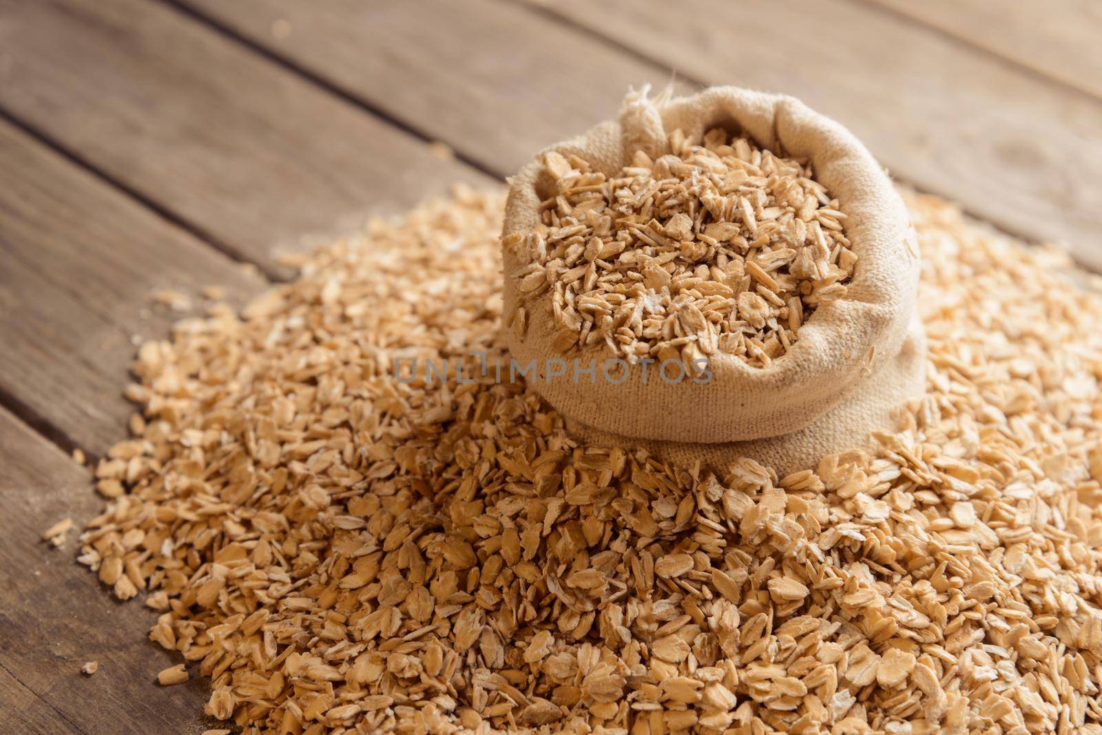 Oatmeal in a burlap bag on a wooden table, top view