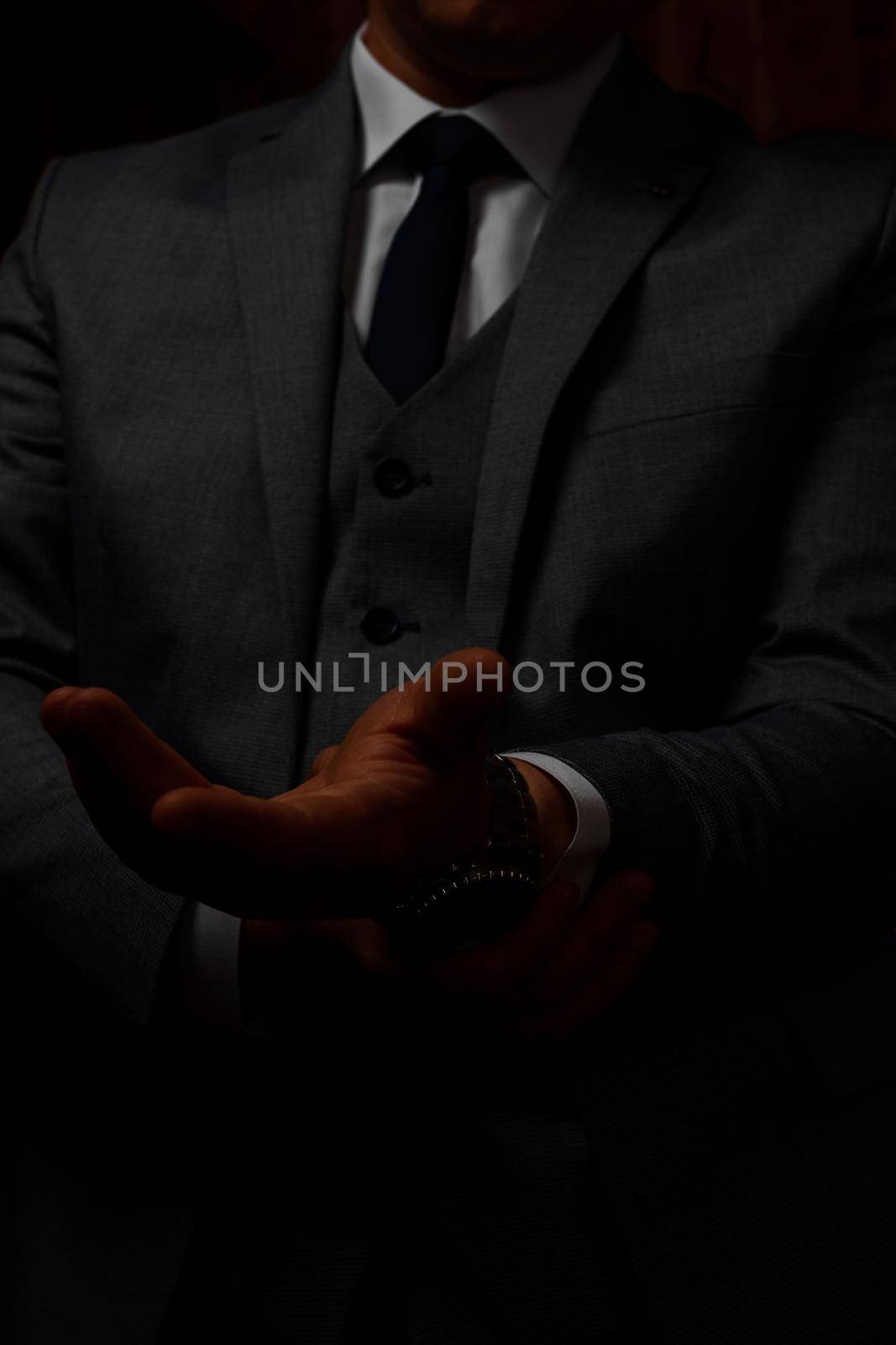 male hands close up, the groom is preparing in the morning before the wedding ceremony. Man adjusts a watch on his hand on a dark background. by Niko_Cingaryuk