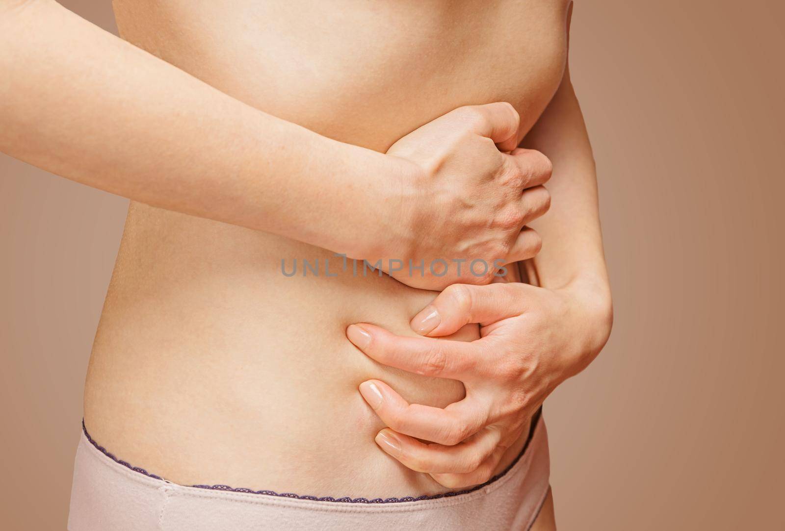 Unrecognizable woman holds her abdomen, side view, abdominal or menstrual pain