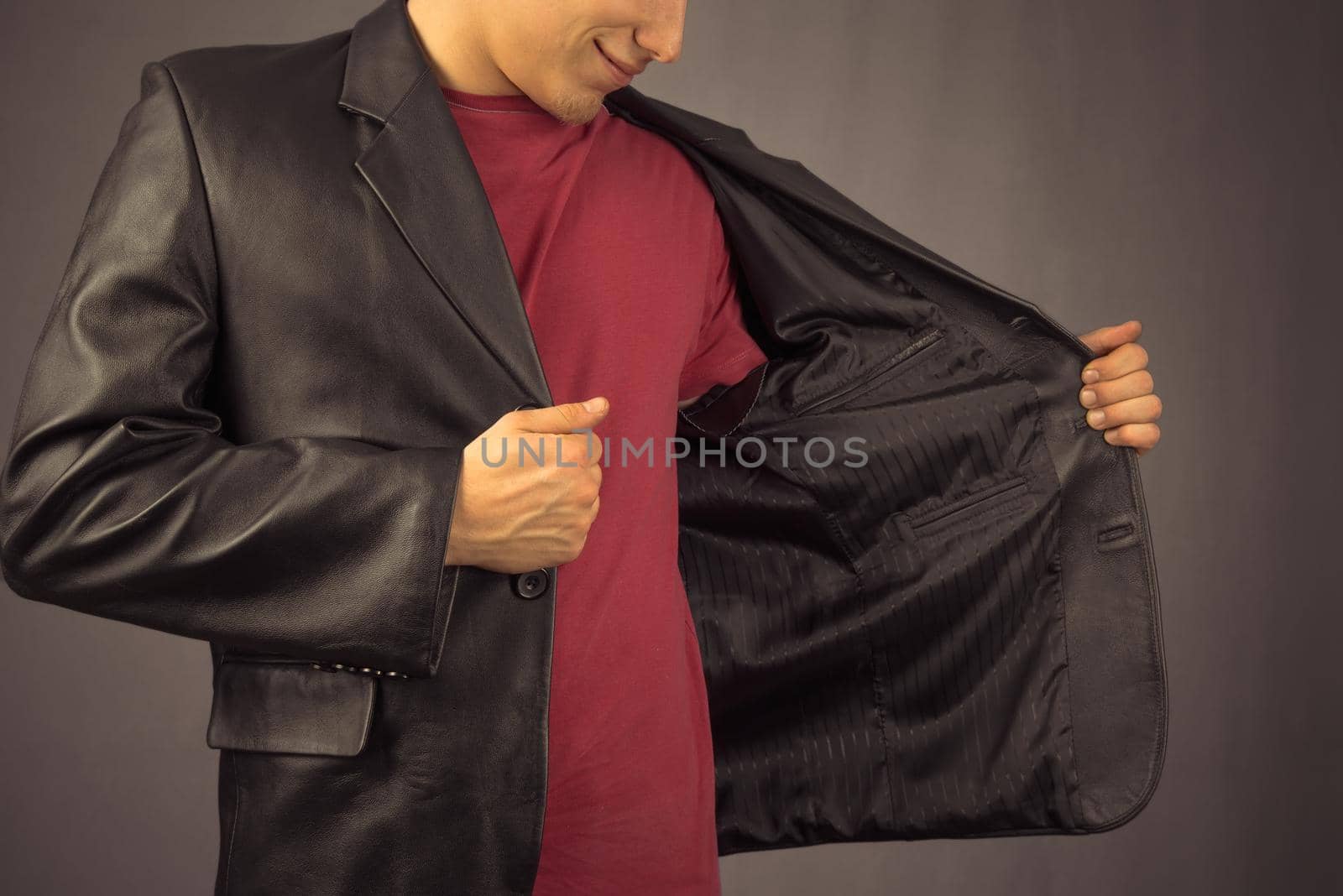 Young man opens his black jacket, space for text