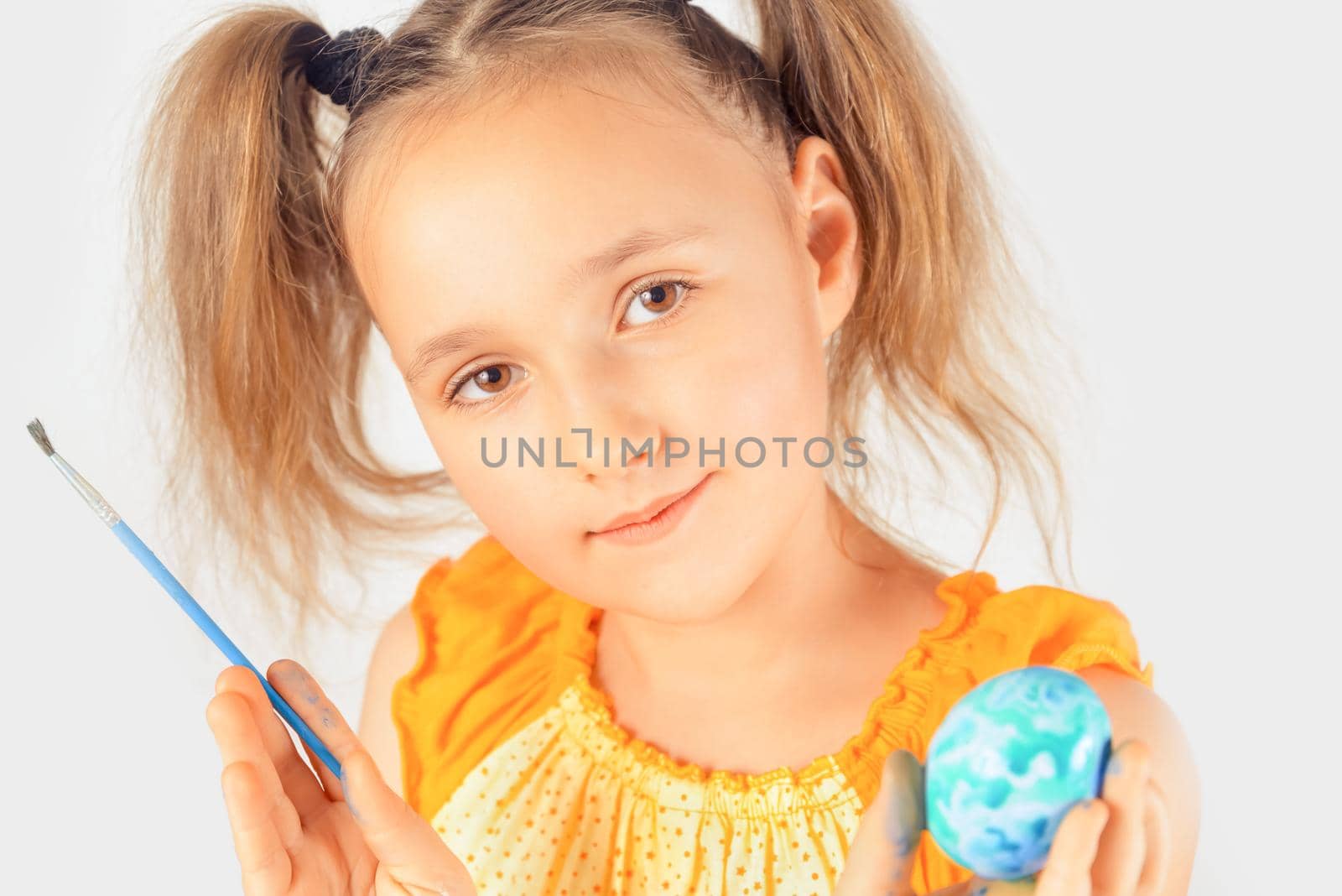 Happy little girl holds an Easter egg and paintbrush