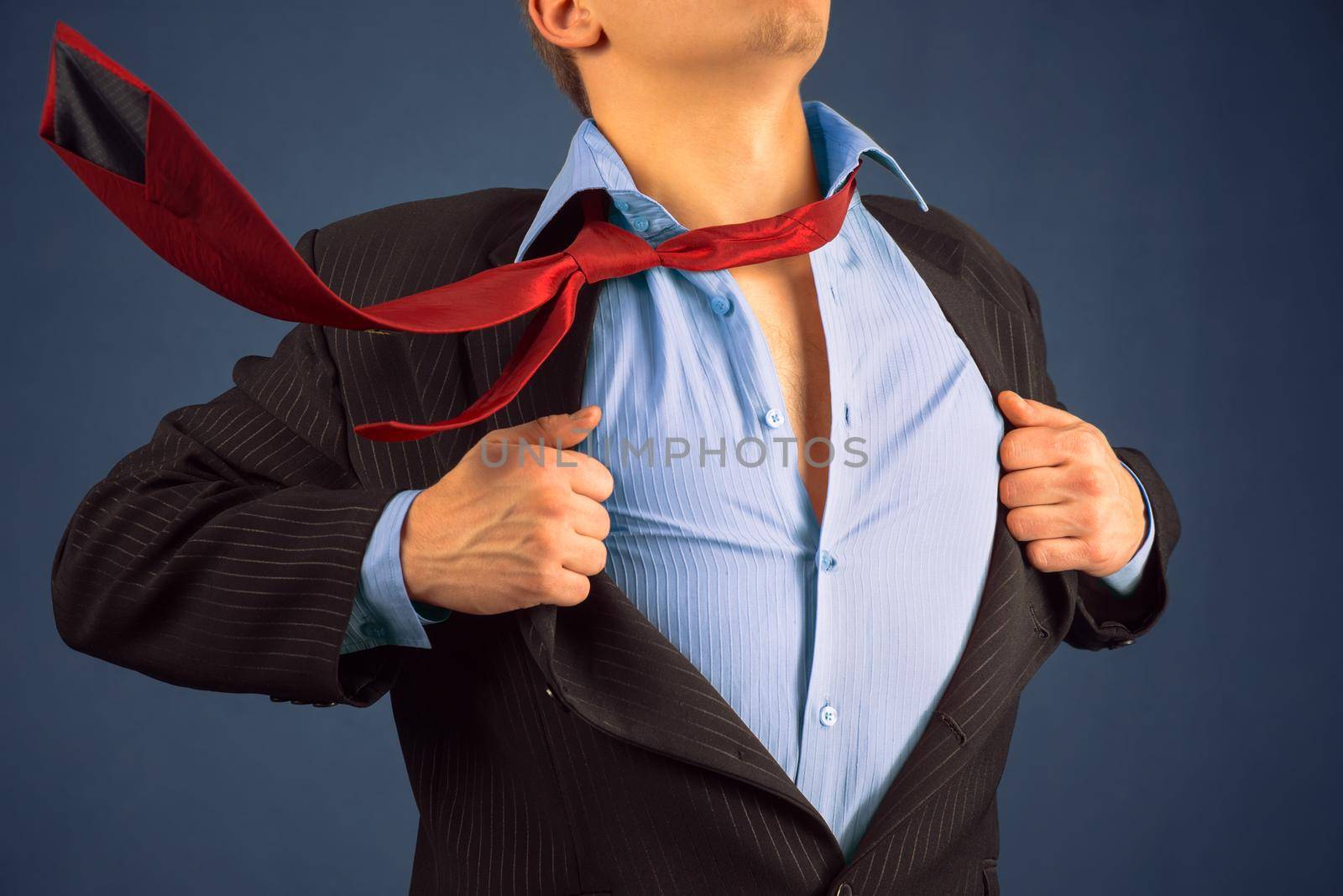 Young businessman opens suit showing his blue shirt on background of sky