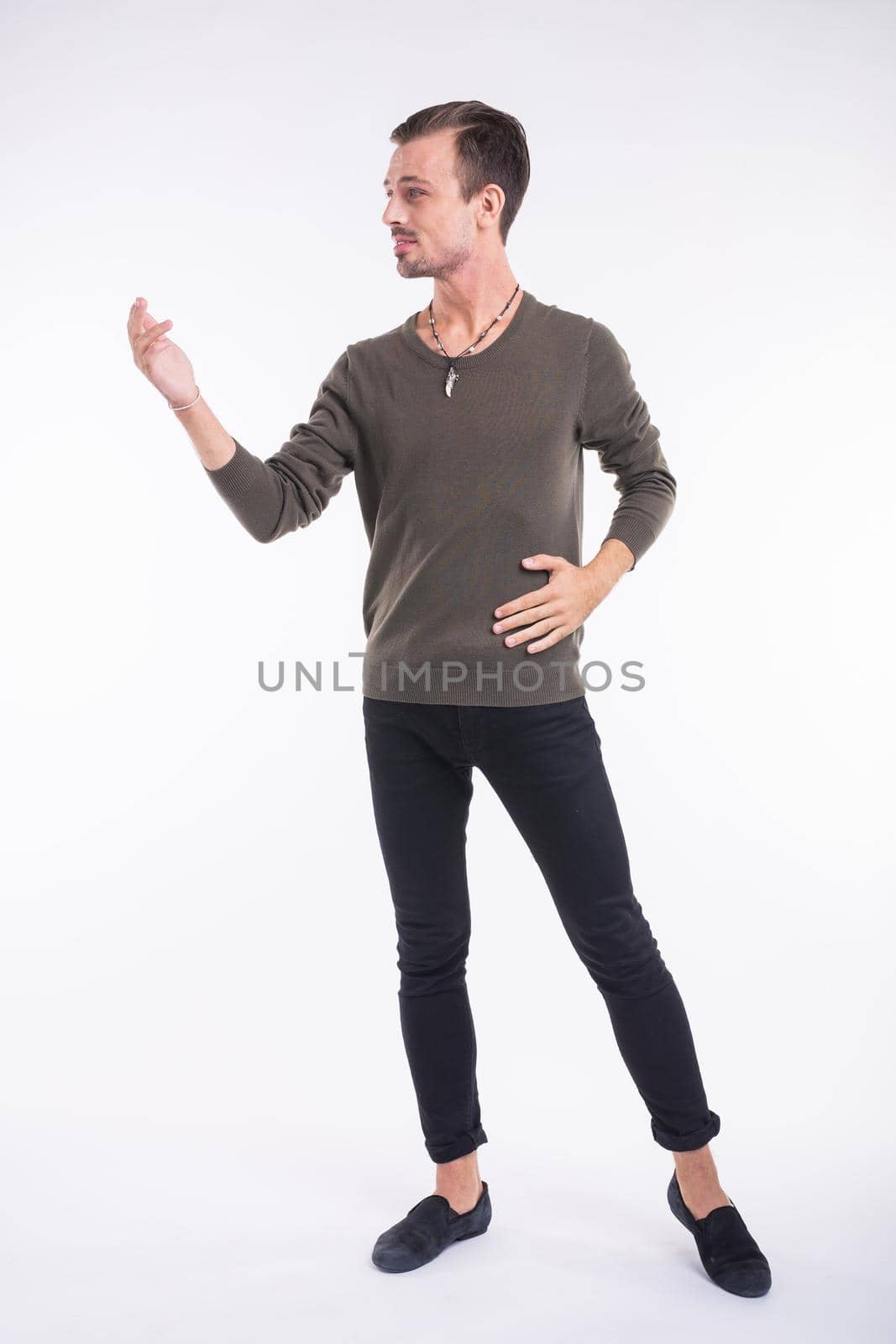 Attractive young man dancing, having fun on white background. Stylish outlook