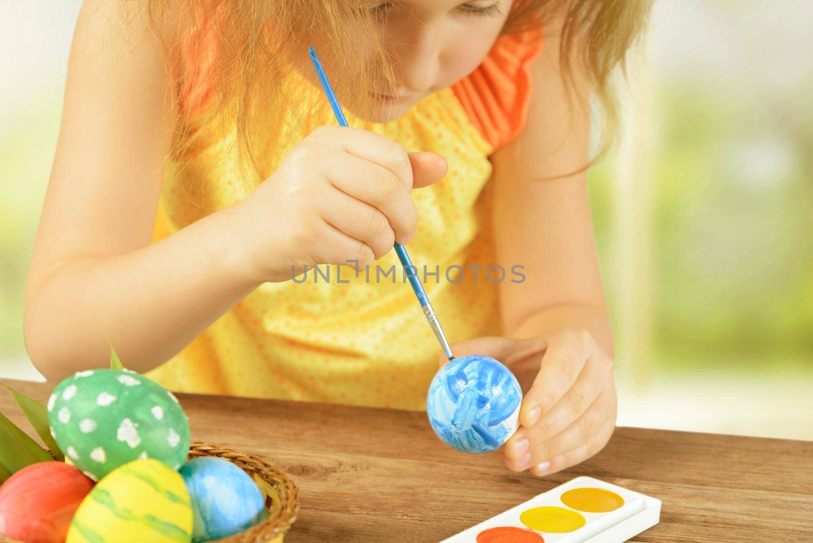 Little girl is painting egg for happy Easter holiday