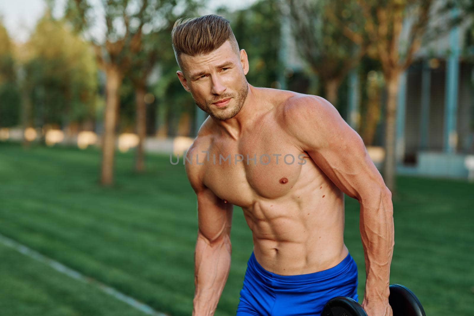 sporty man with pumped up body in park workout exercise. High quality photo