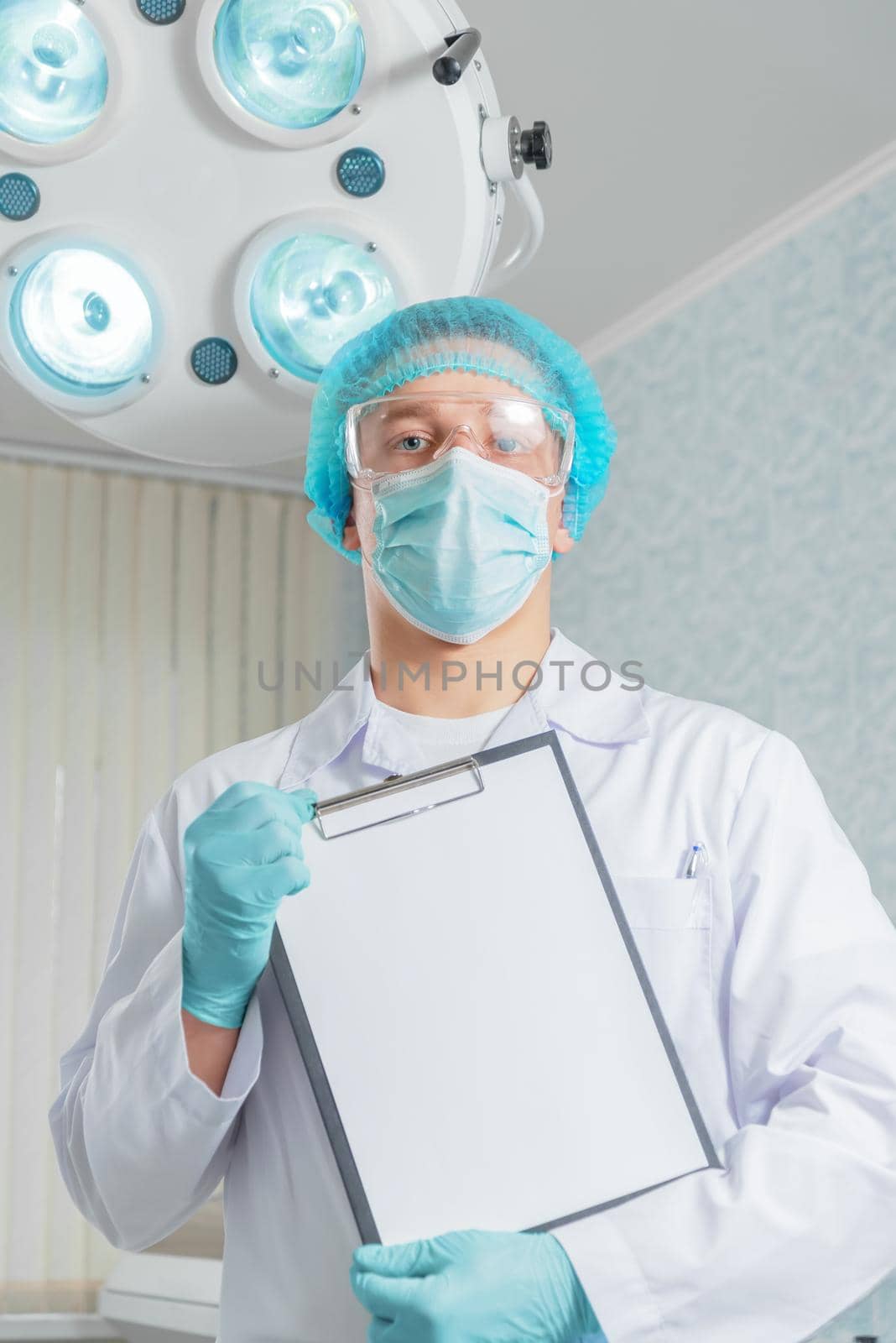 Man doctor surgeon holds empty clipboard in a hospital, space for text