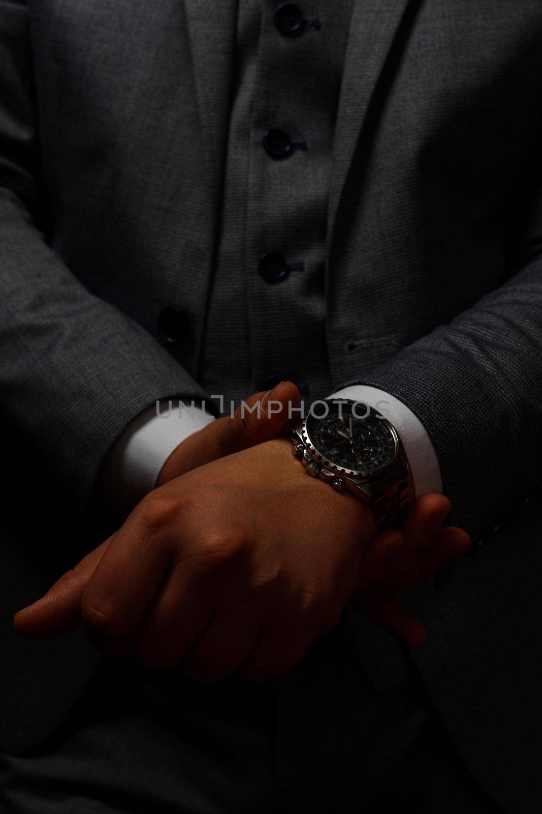 male hands close up, the groom is preparing in the morning before the wedding ceremony. Man adjusts a watch on his hand on a dark background 2021.