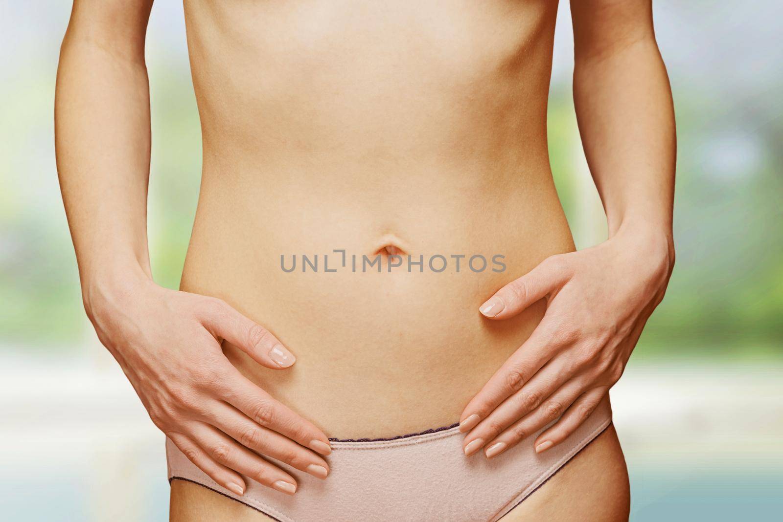 Female slim belly, hands on the abdomen, face is not visible