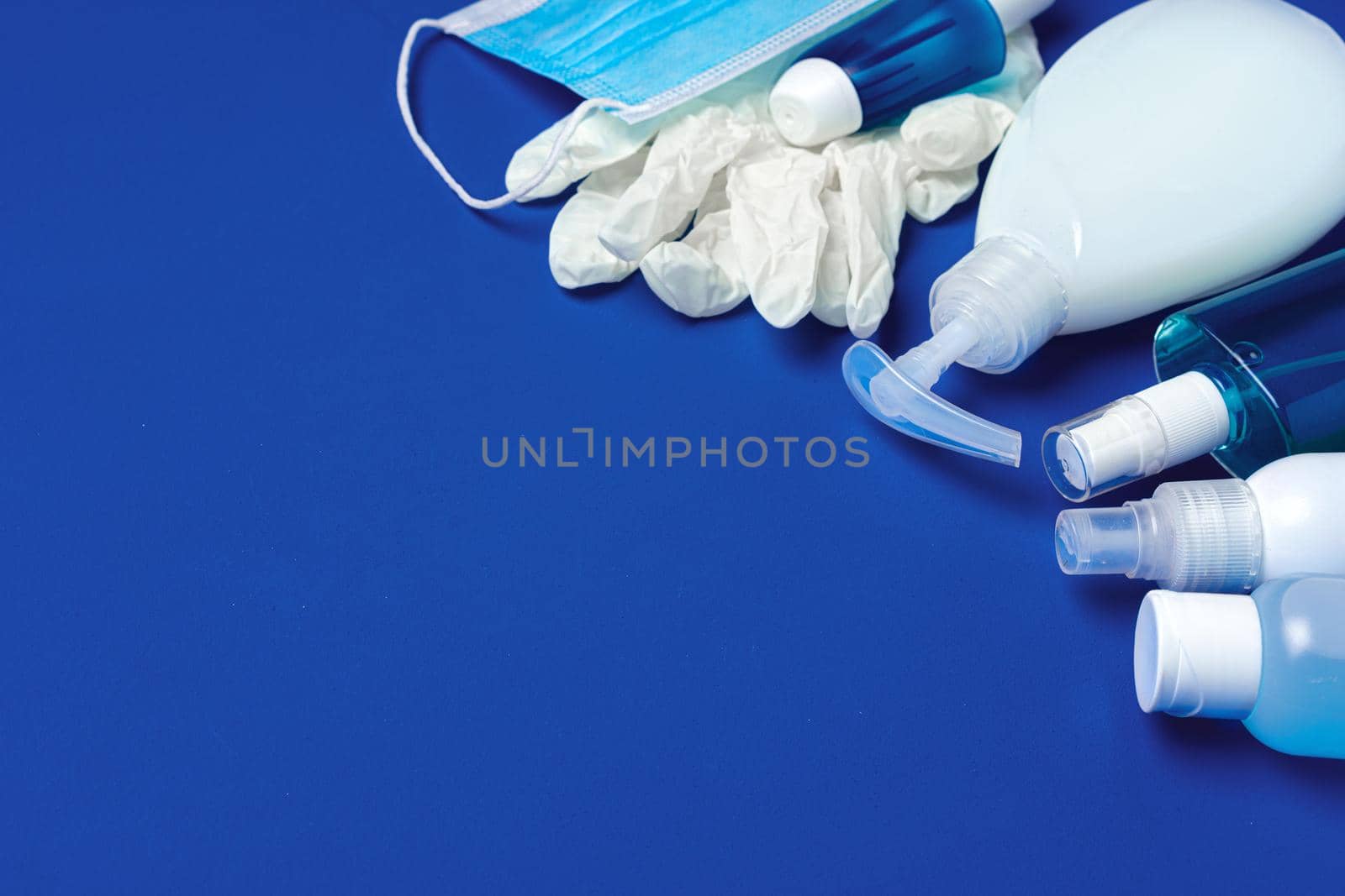 Coronavirus prevention. Facial mask, gloves, soap and sanitizer on blue background close up