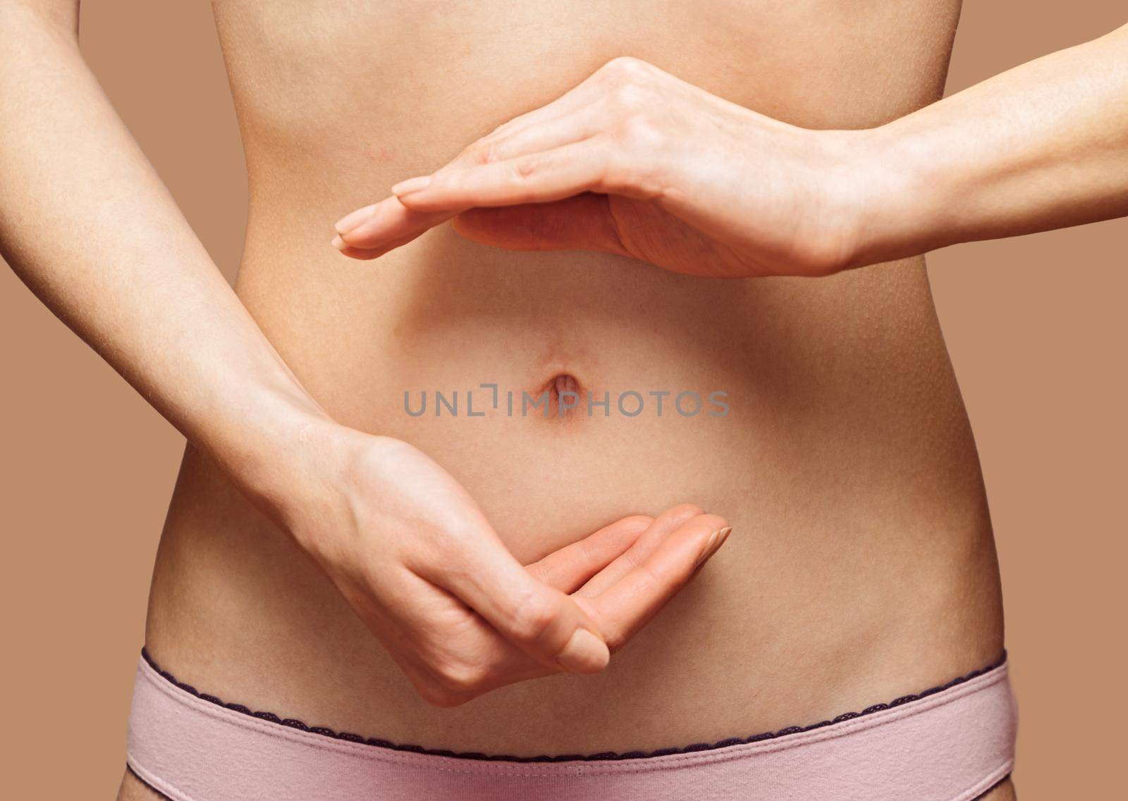 Unrecognizable woman holds her hands in circle shape in front of her abdomen