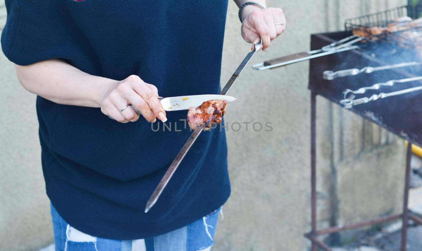 Women's hands cut barbecue meat Skewer on grill