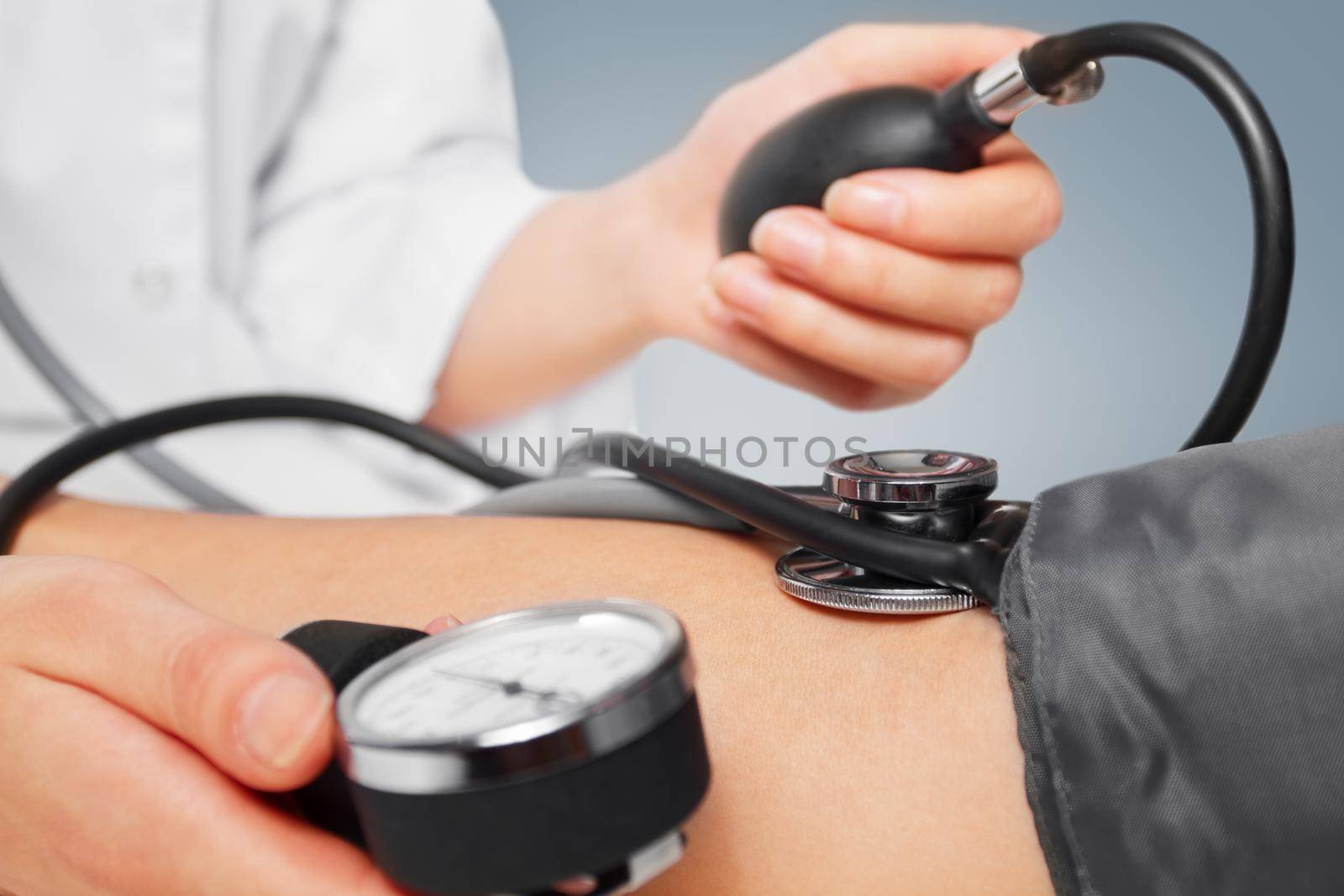 Unrecognizable physician measures blood pressure a patient, close-up