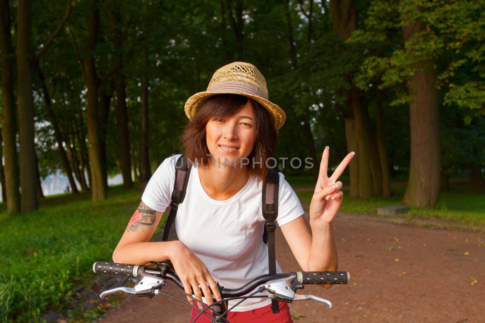 Hipster girl doing victory sign while sitting on a bicycle