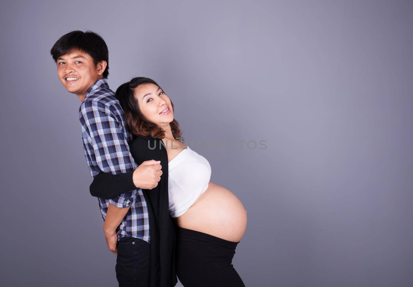 young couple: pregnant mother and happy father on gray background by geargodz