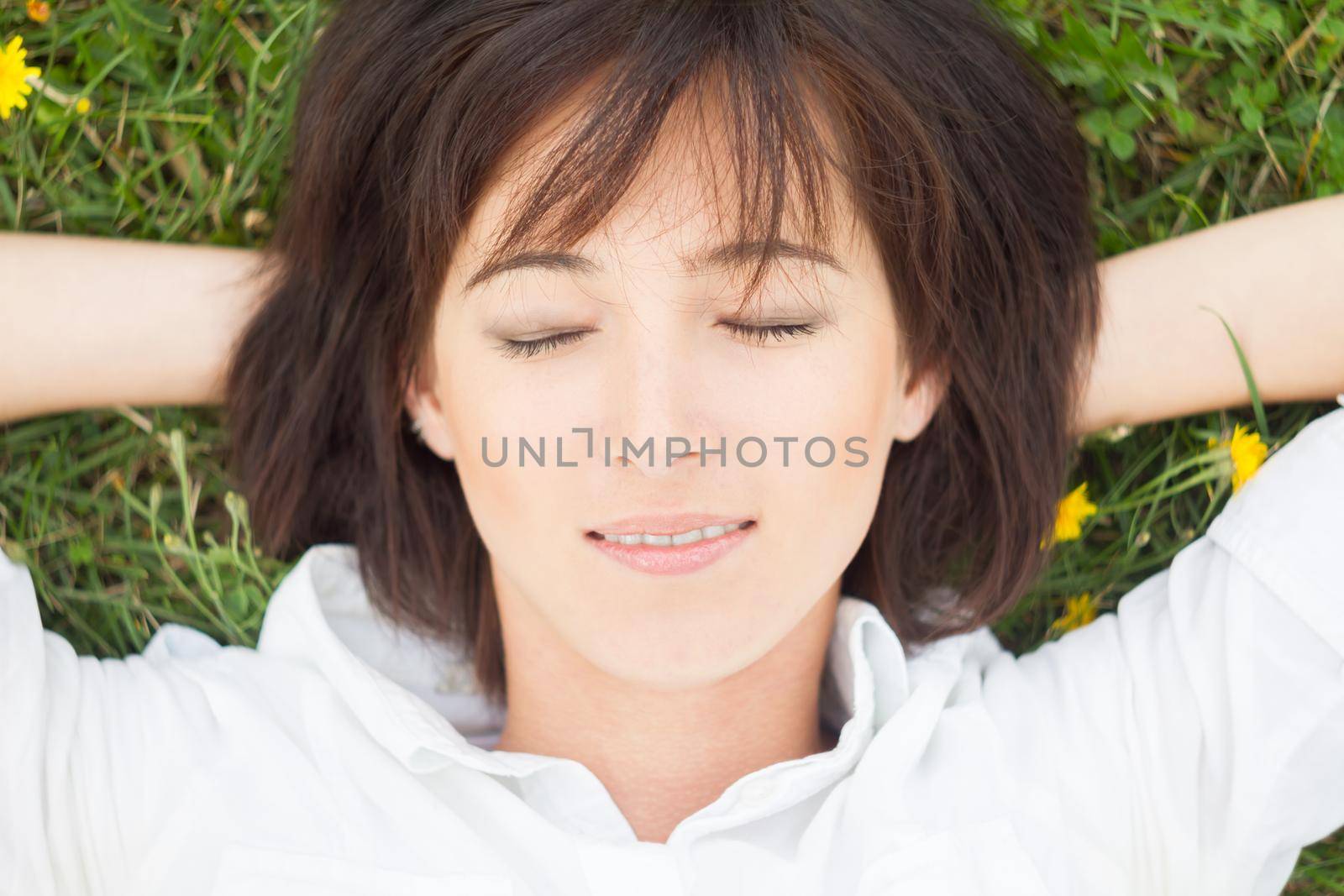Young woman lying on a meadow with eyes closed, close-up