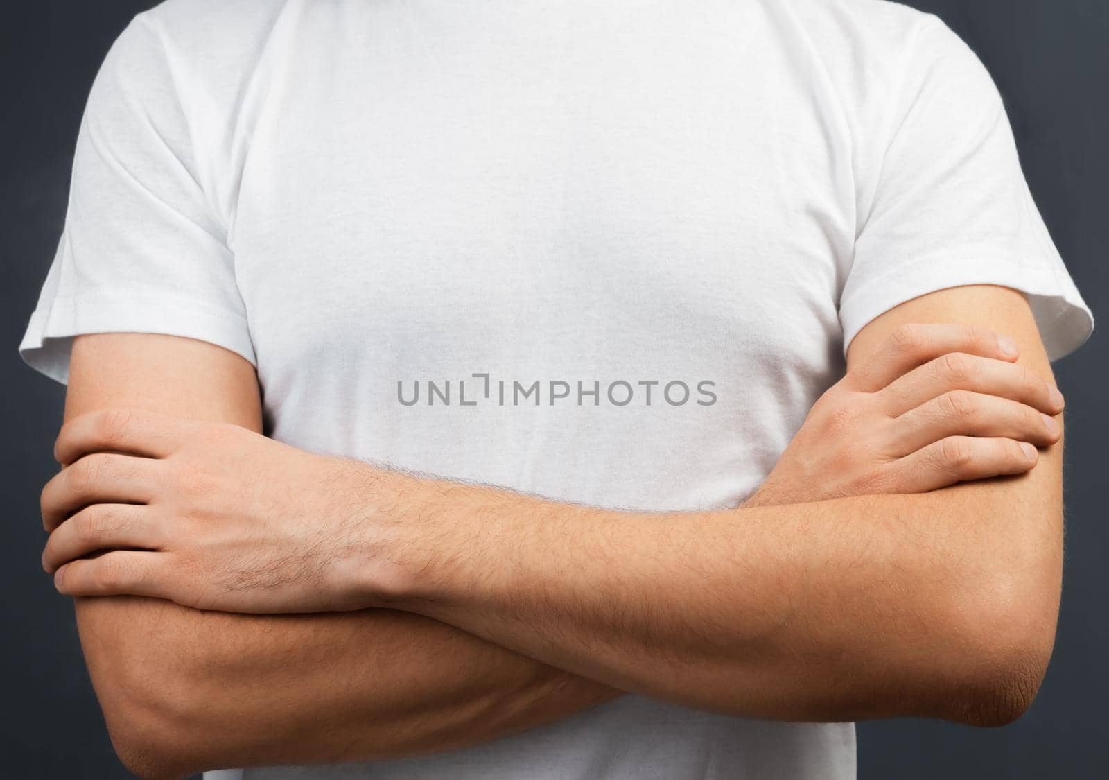 Man stands in white t-shirt with hands on his chest, space for text