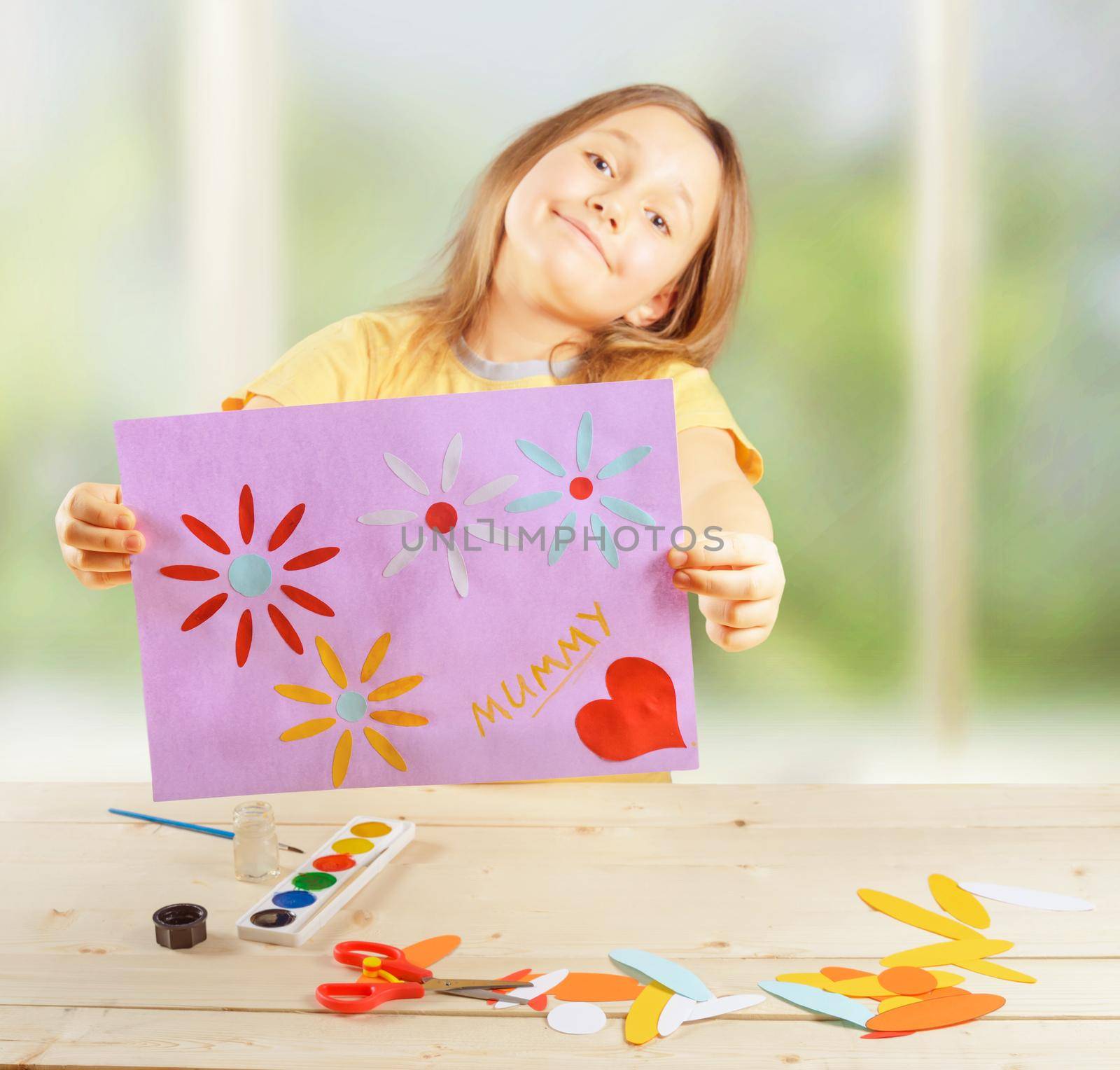 Happy little girl holds greeting card for mothers day