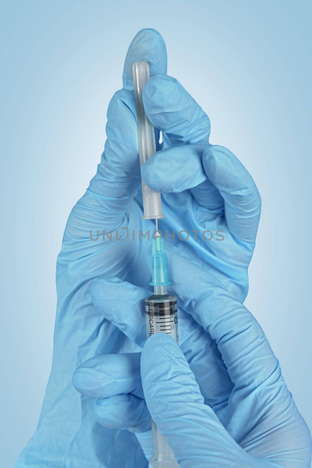 Human hands in gloves is holding syringe on a blue background