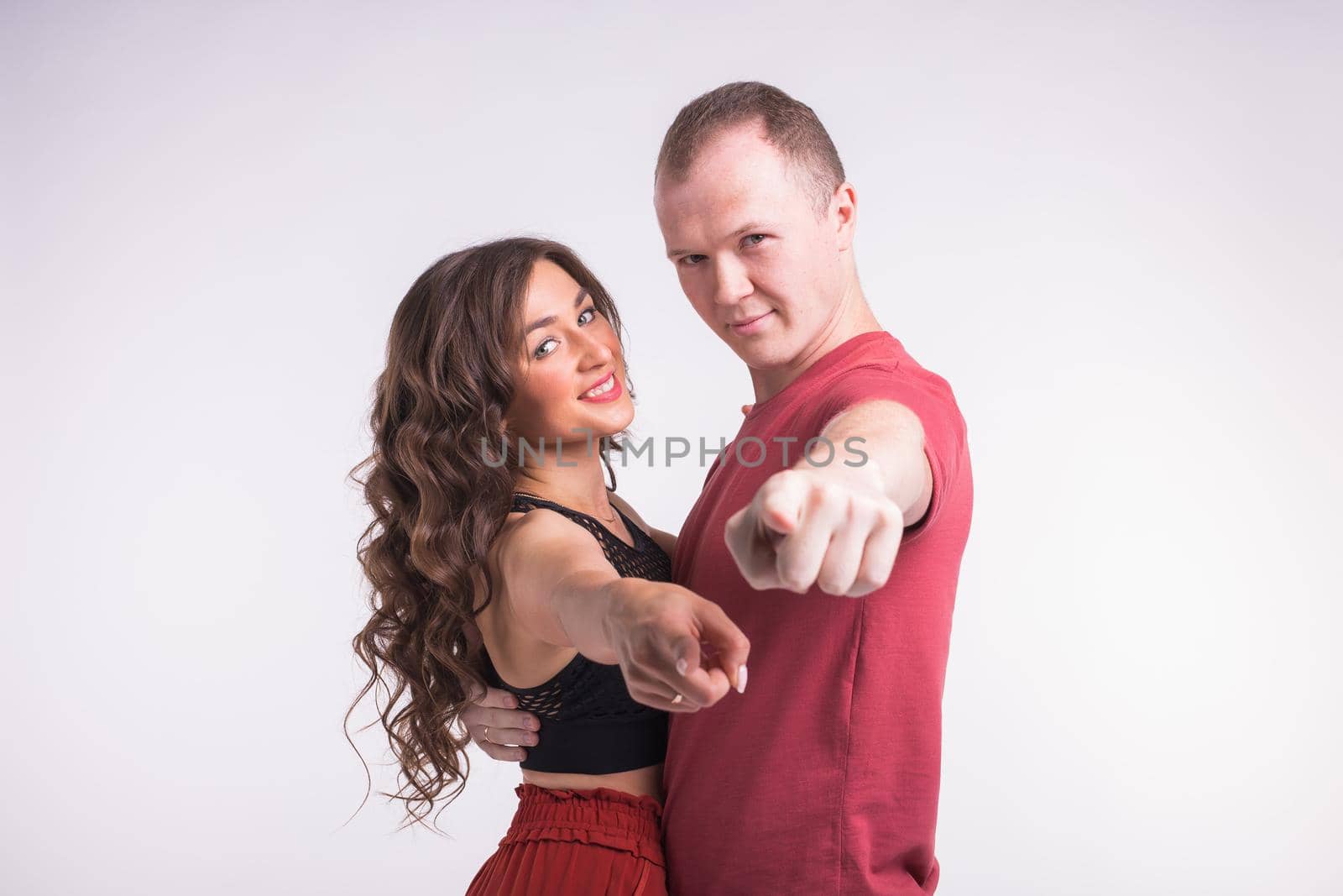 Portrait of young healthy sporty couple hugging on white background