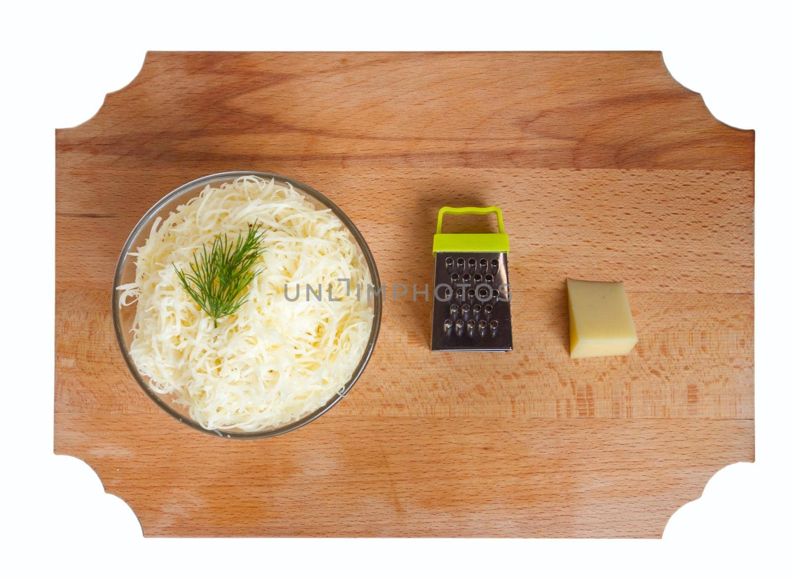 Grated cheese in a bowl with dill, grater on a wooden table. Top view.