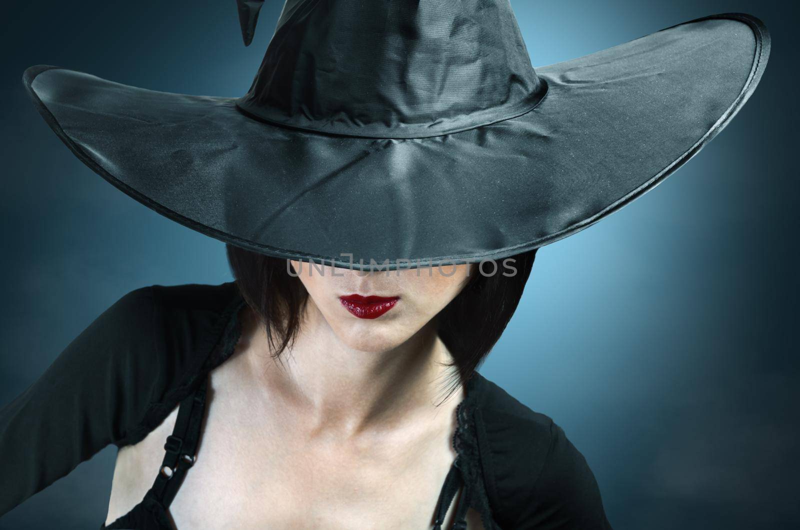 Young woman in a witch costume, her face covered with a hat