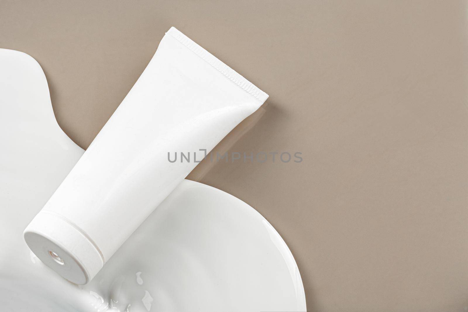 Blank white skincare product tube on beige background with copy space