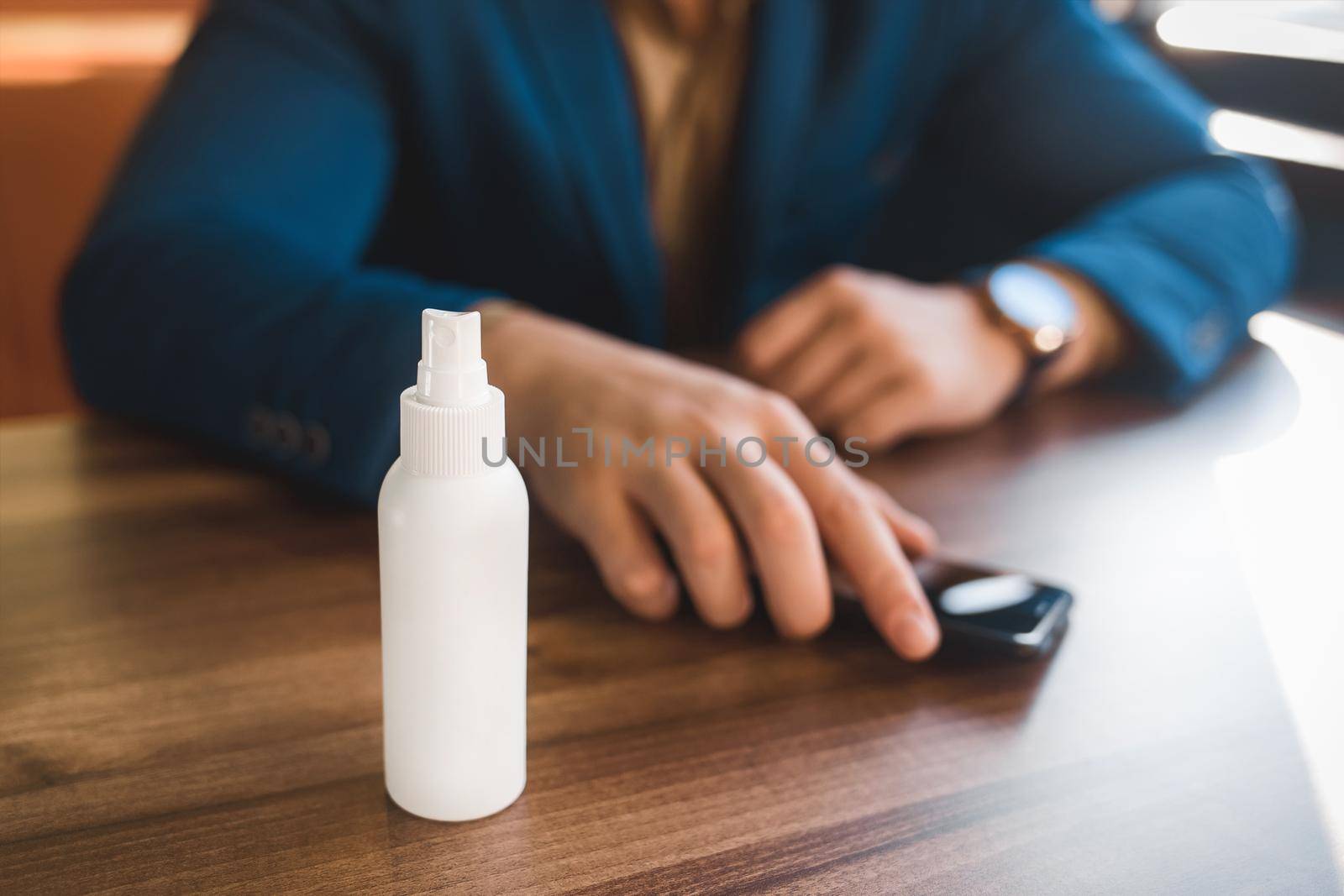 Antiseptic on the background of the hands of a businessman take the phone on the table.