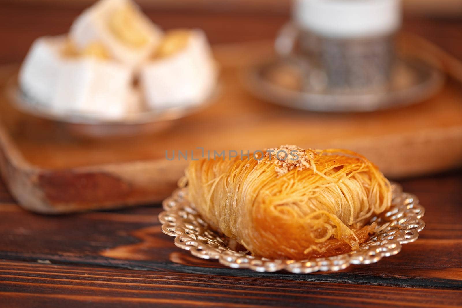 Turkish sweets on small plate on brown wooden background, close up