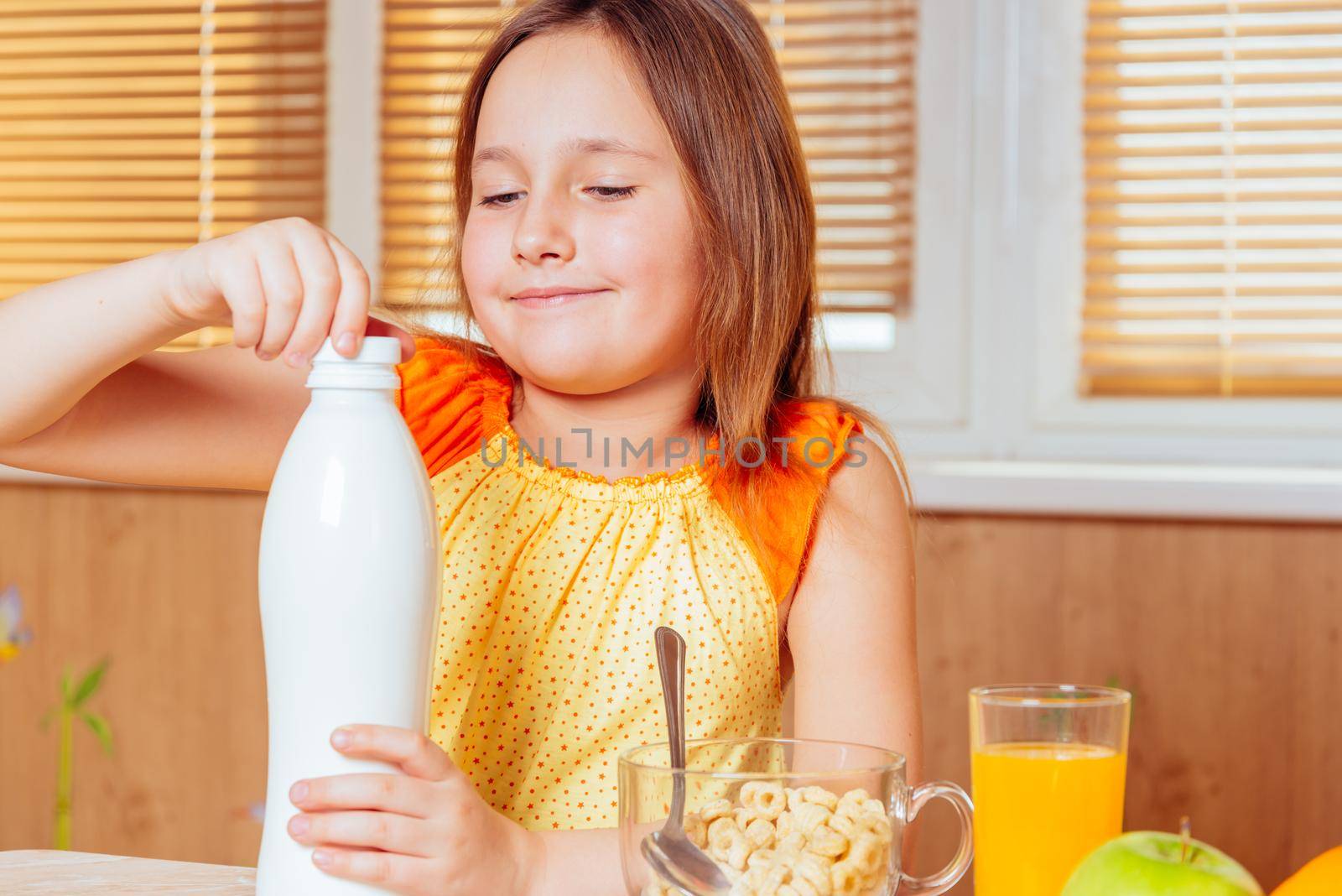 Little girl opens bottle of milk for cereal flakes