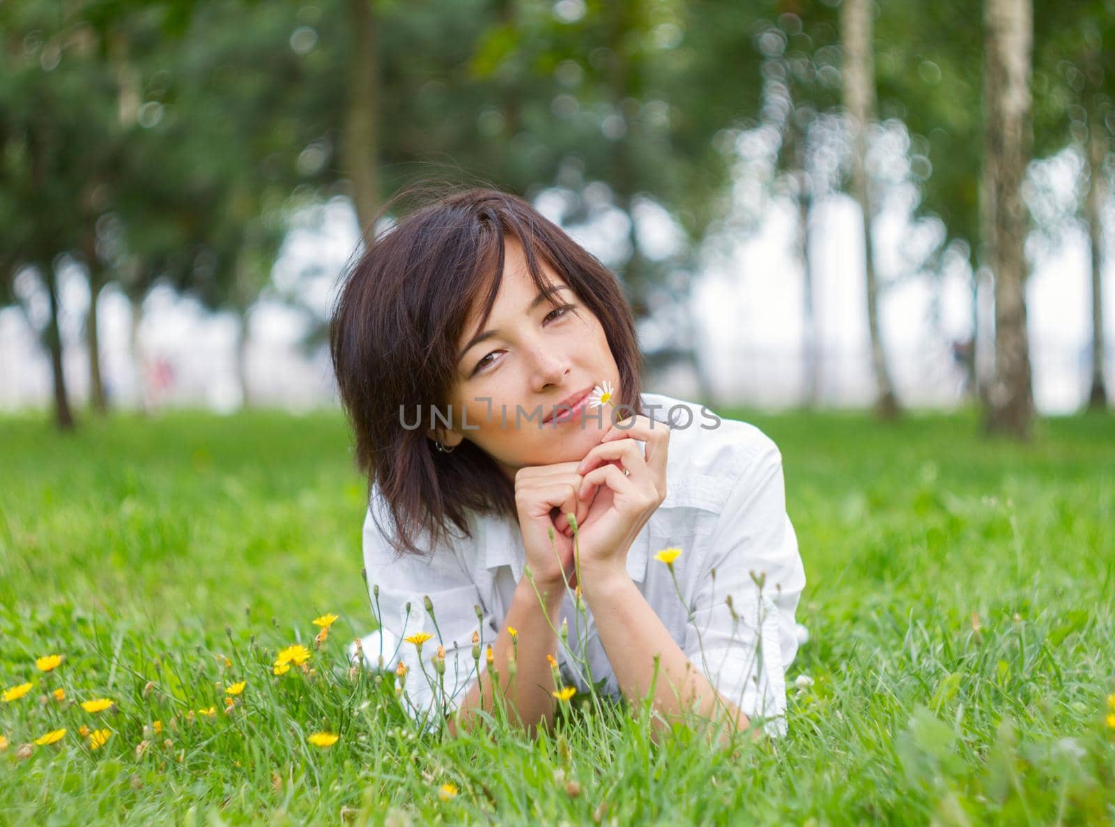 Beautiful young woman smiling with daisy in natural environment