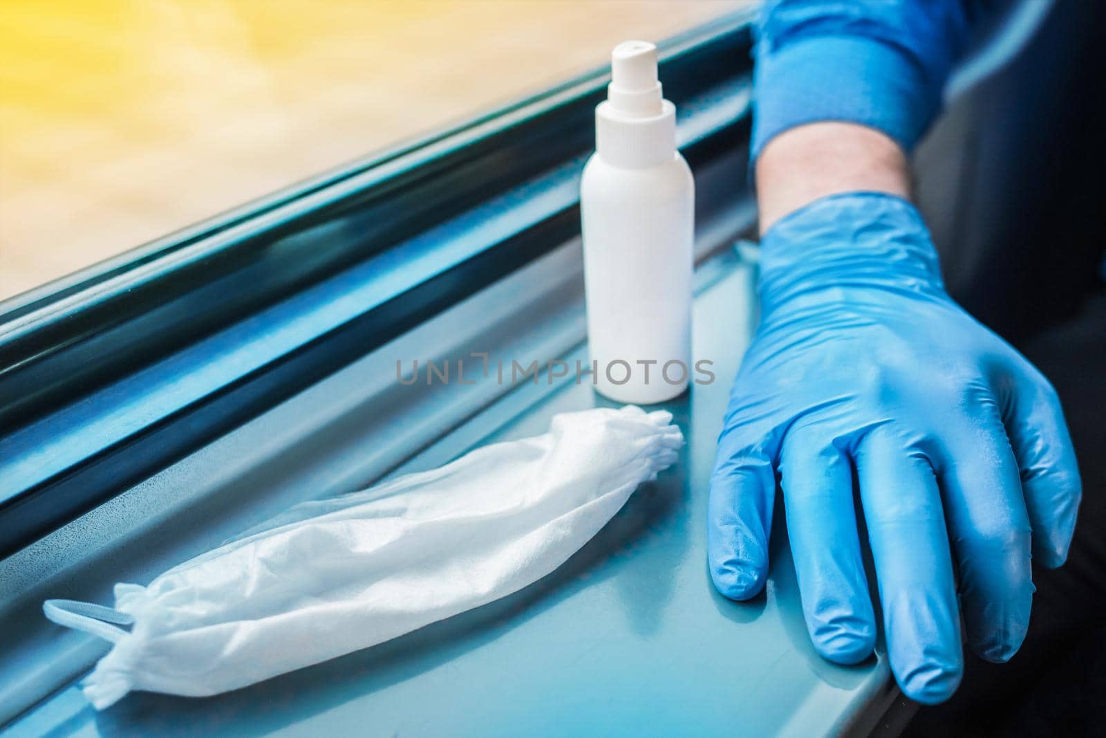 A person's hand in a protective medical glove lies next to a used medical mask and antiseptic. Hygiene and safety concept against coronavirus.