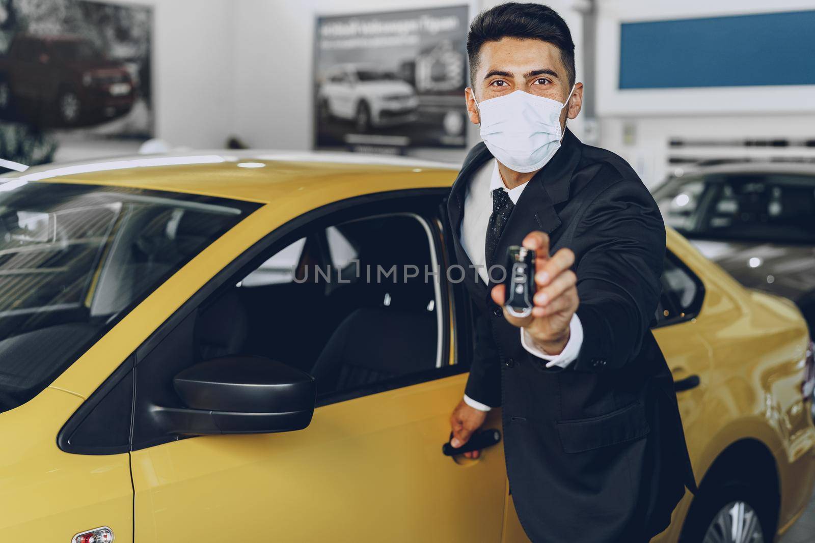 Man car dealer wearing protective medical mask on his working place, coronavirus prevention concept