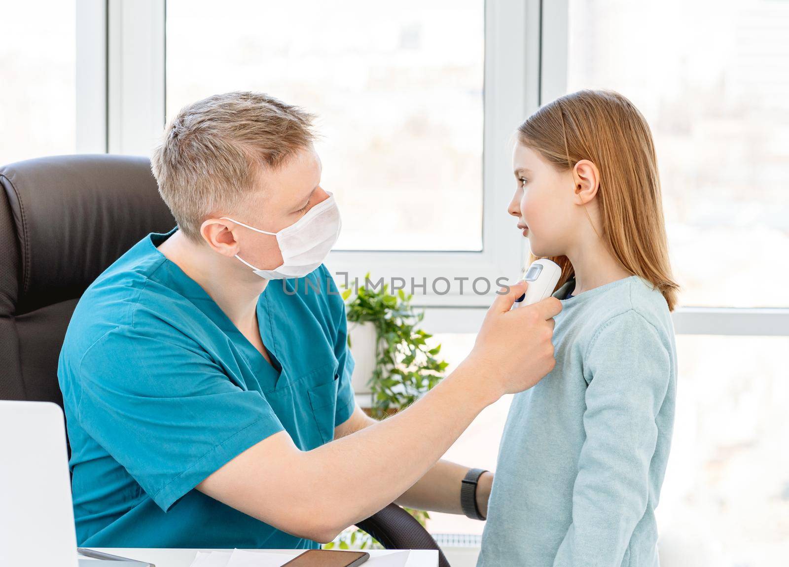 Cute little girl measuring temperature at doctor