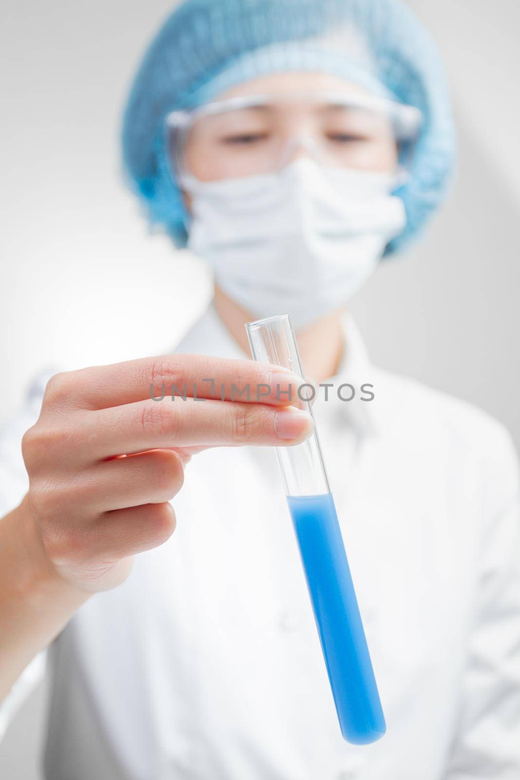 Lab technician looking at test tube blue color