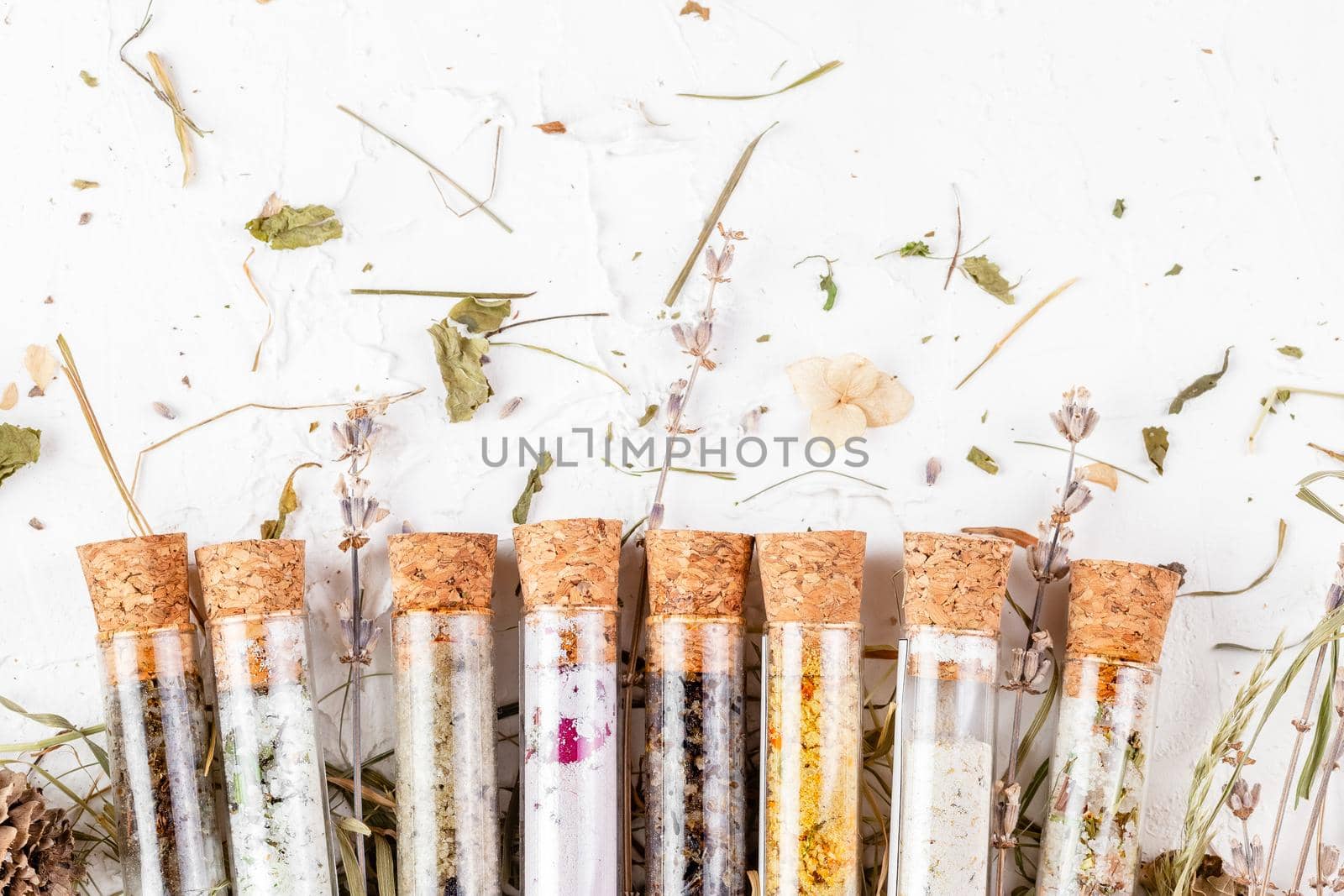 Flat lay of bath salts set in glass tubes with dry herbs around. Natural organic SPA cosmetic product. Skin care, beauty treatment concept