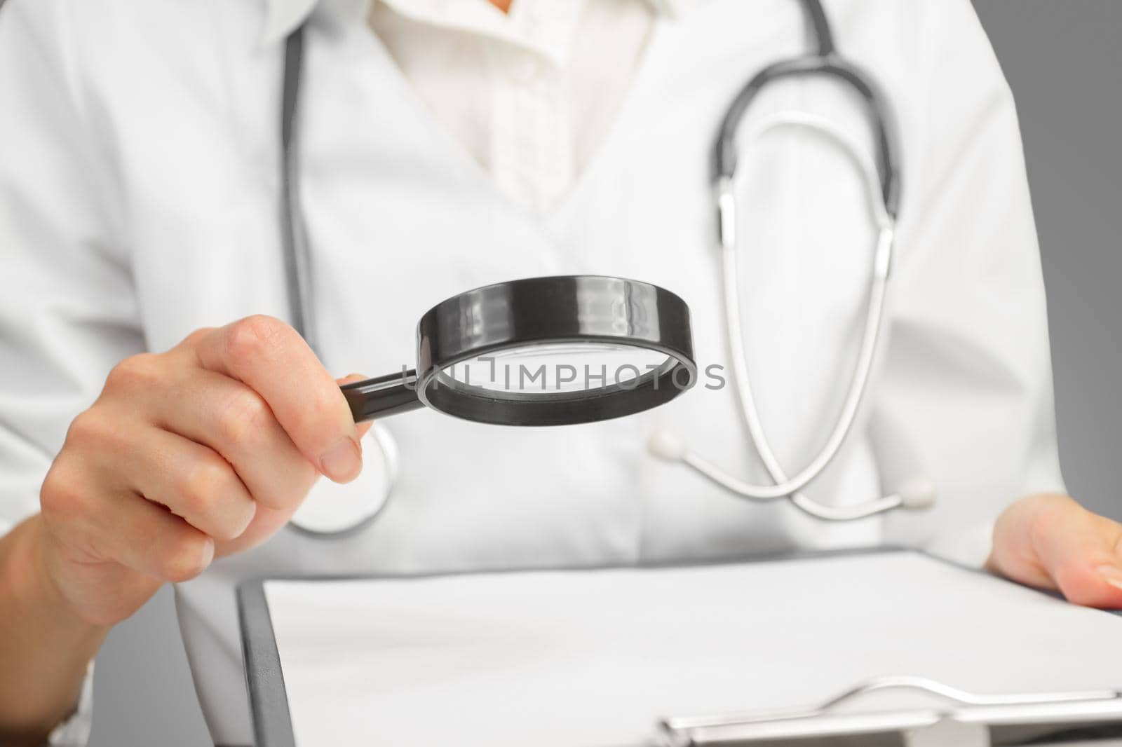 Doctor Looking Through Magnifying Glass On Gray Background. Space for text