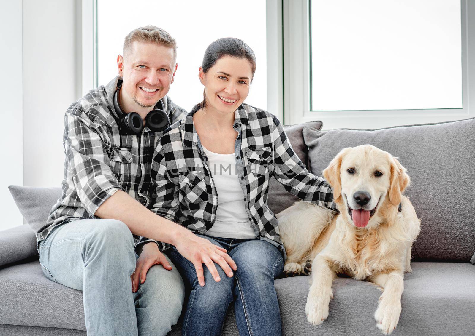 Smiling couple palming golden retriever at home