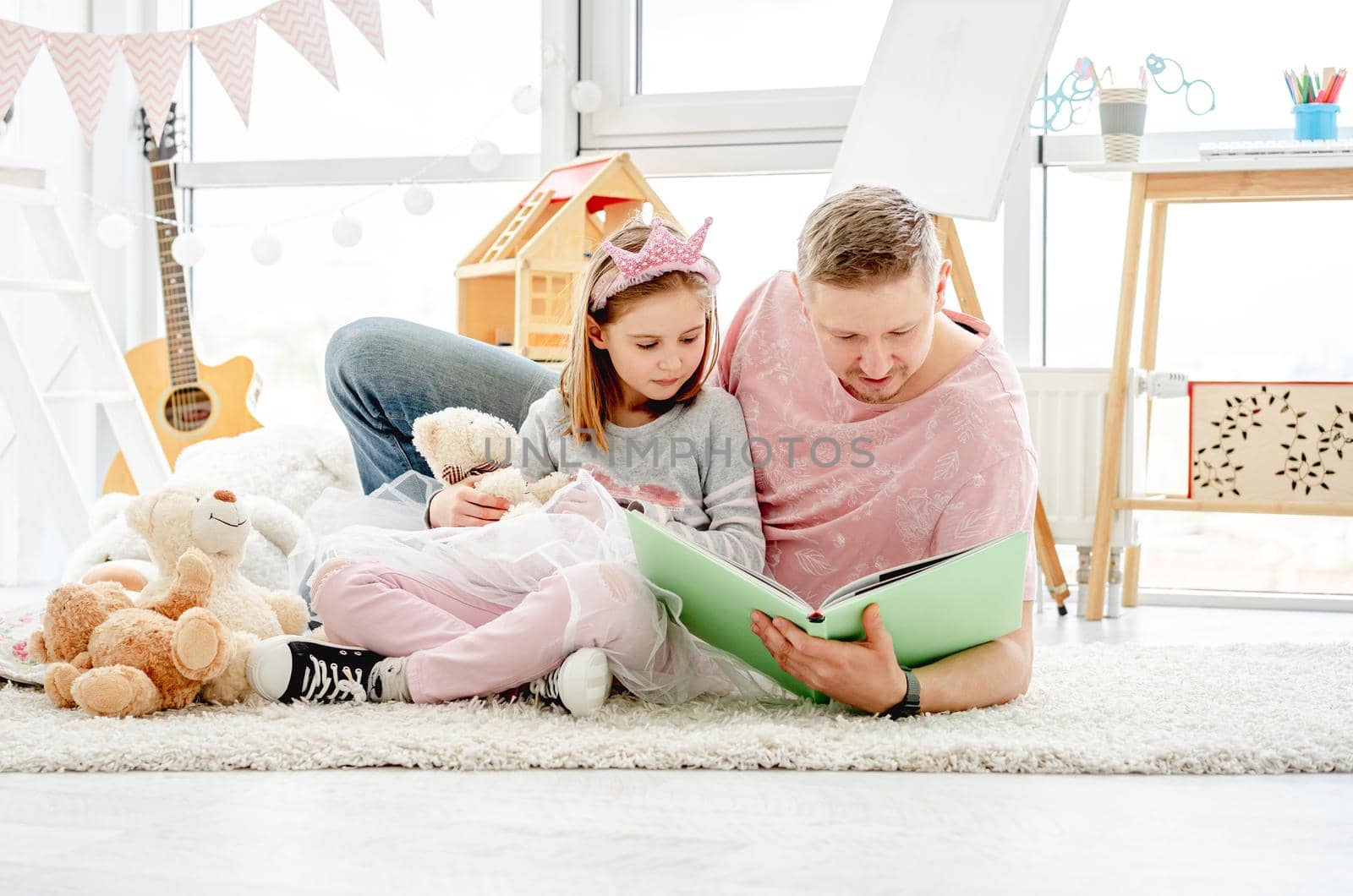 Cute little daughter with happy father reading book