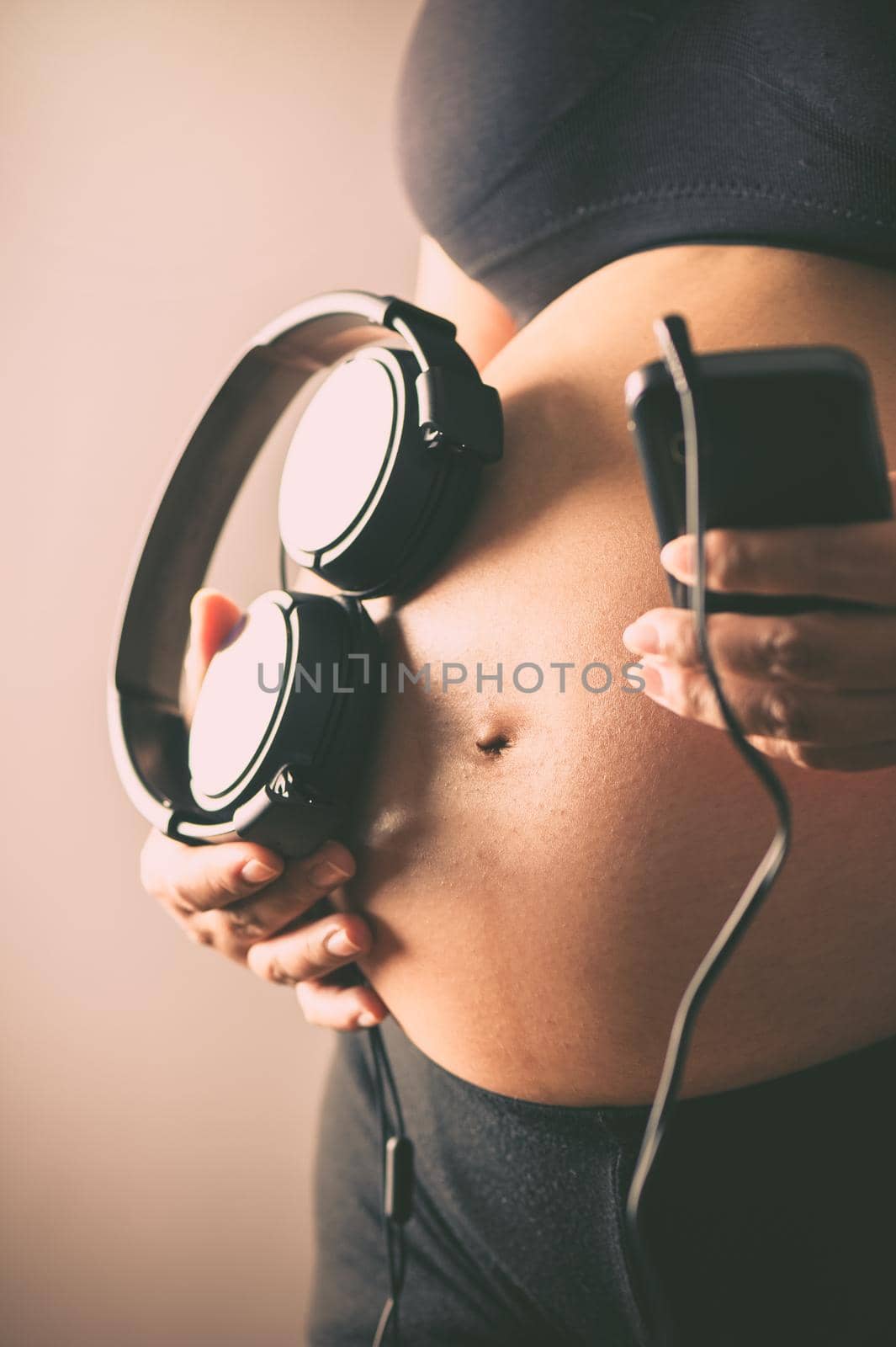 Pregnant woman holding headphones on her belly