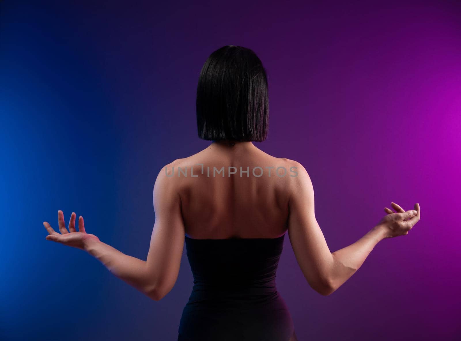 strong muscular back of a brunette girl on a neon background by Rotozey