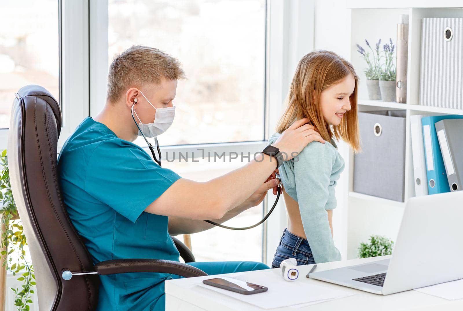 Doctor listening little girl by phonendoscope in clinic