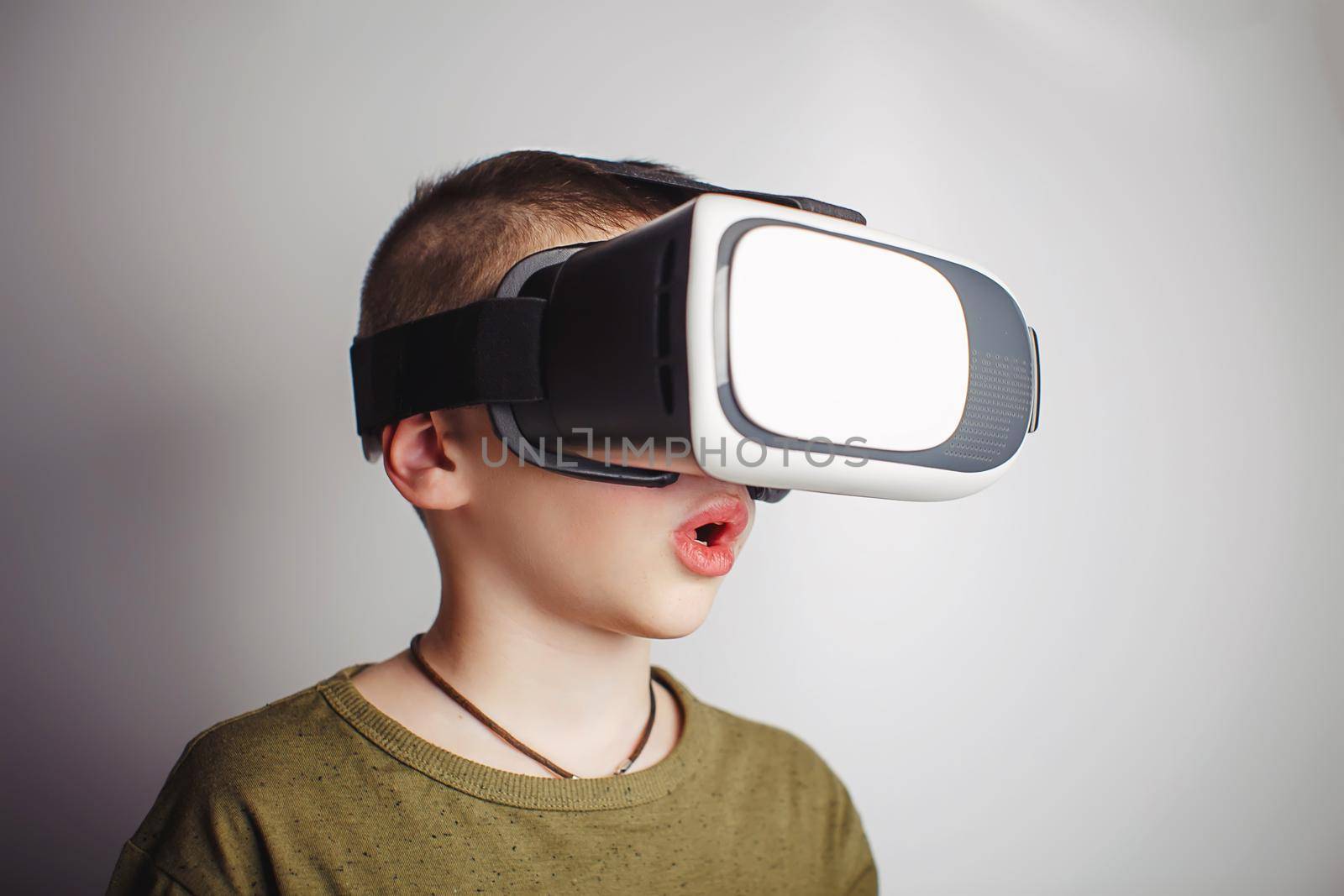 Boy playing mobile game app on device virtual reality glasses on white background. Boy action and using in virtual headset, VR box for use with smart phone. Contemporary technology concept, close up