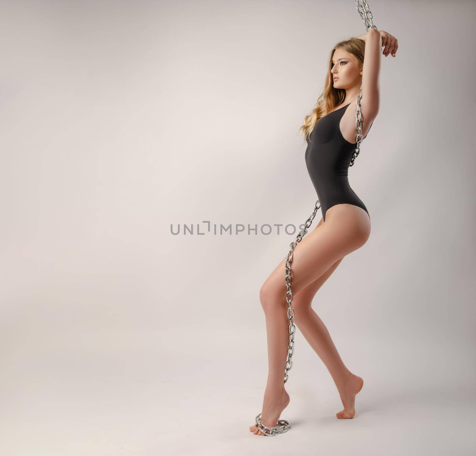 the sexy slender girl in a bodysuit posing with a large chain